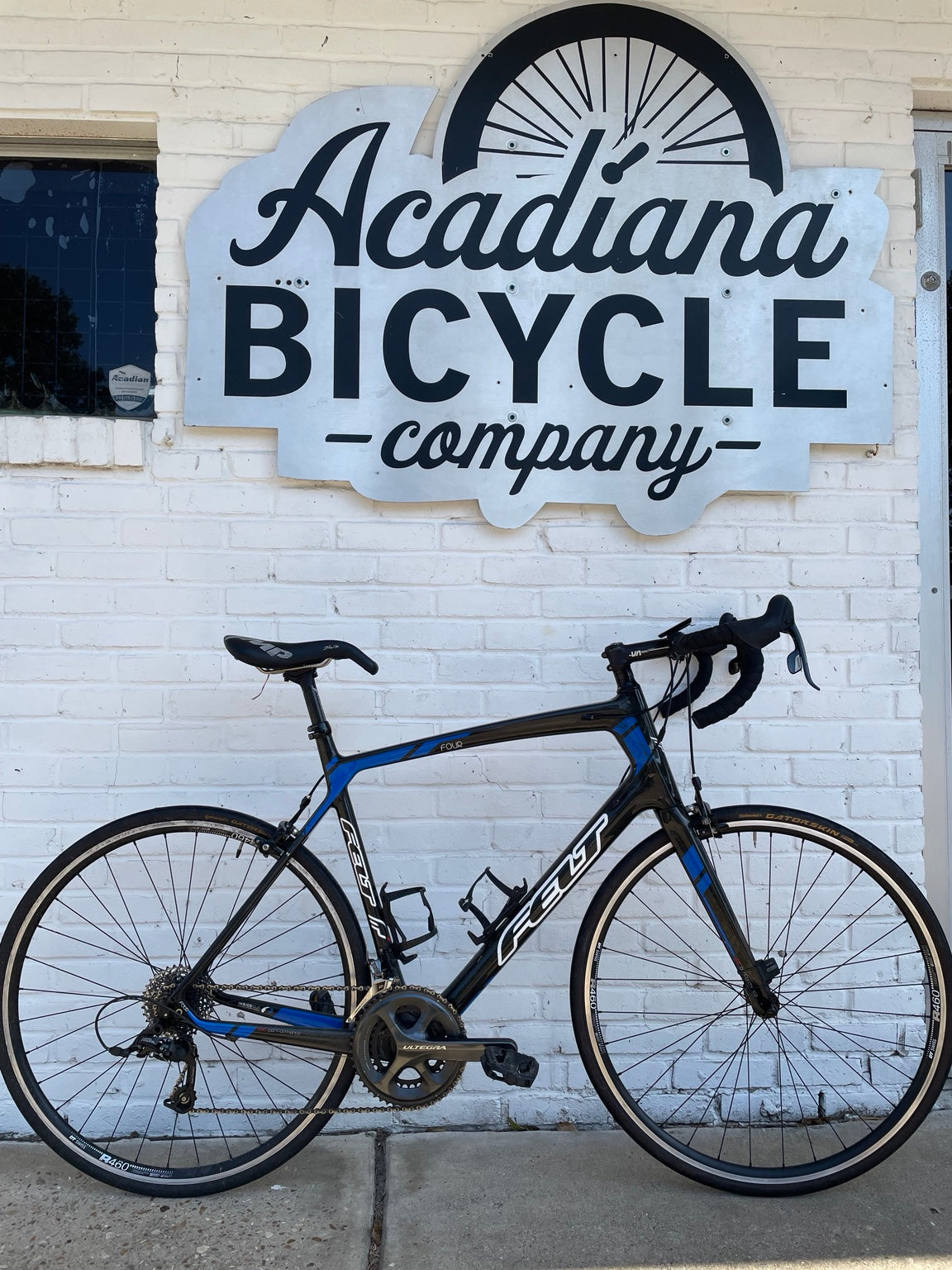 Black and blue Felt Four carbon road bicycle with Shimano Ultegra crankset outside Acadiana Bicycle Company