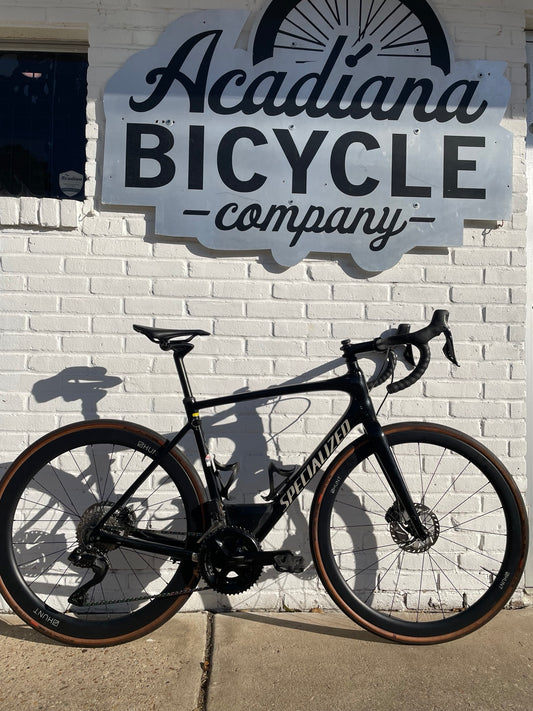 Black Specialized Roubaix carbon road bicycle with HUNT deep-section wheels outside Acadiana Bicycle Company