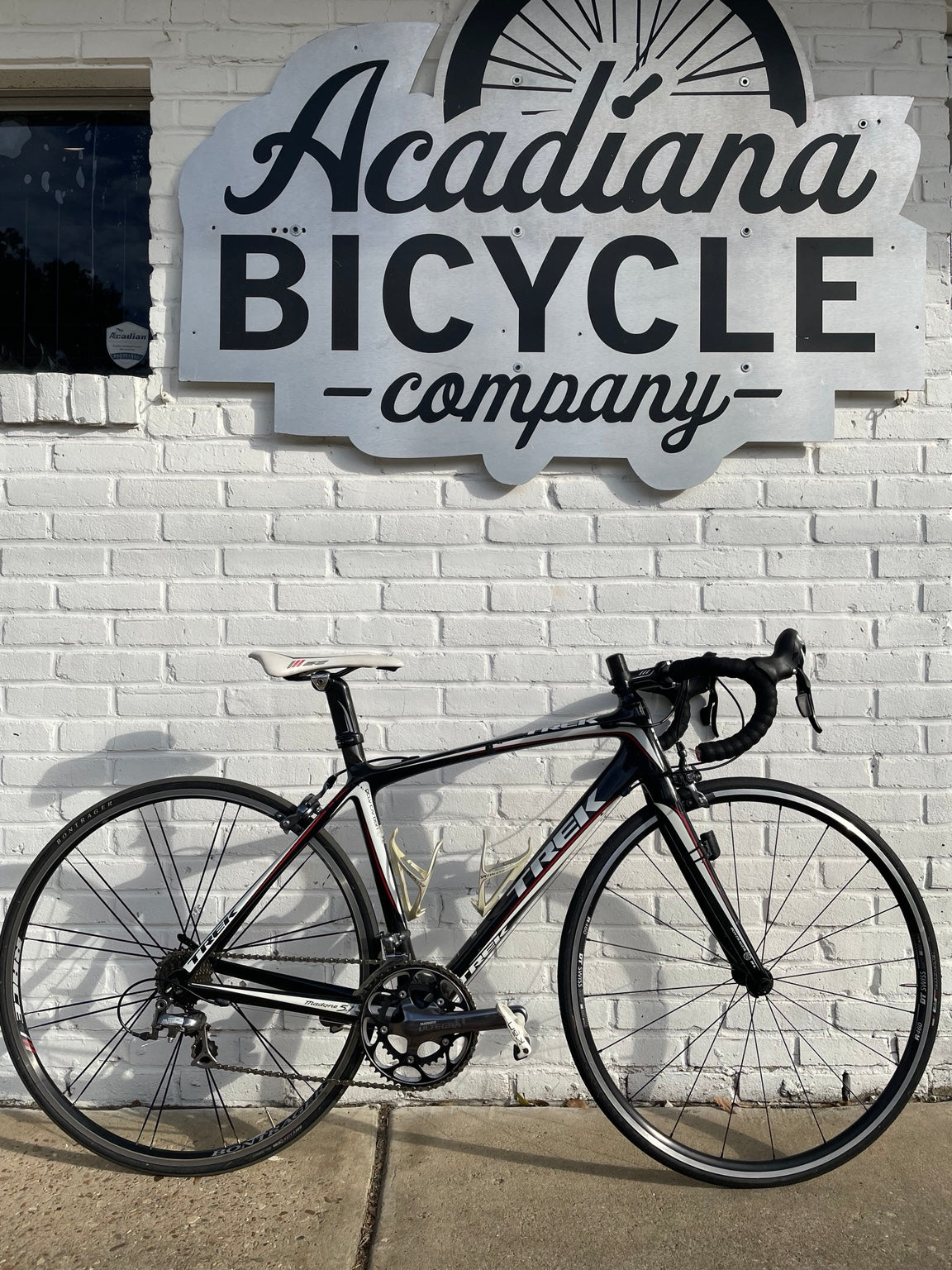 Used black white red Trek Madone carbon road bike outside Acadiana Bicycle Company